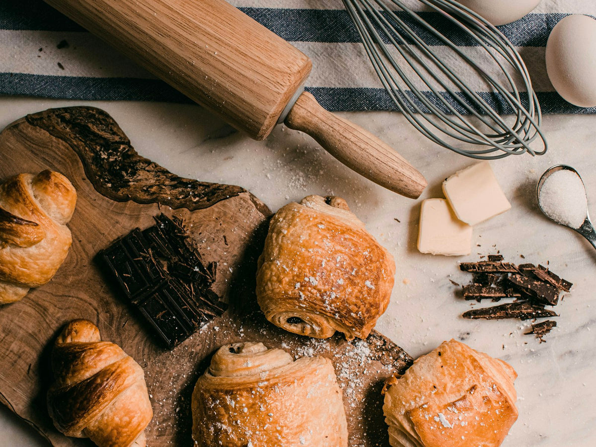 Viennoiseries et ustensiles de pâtisserie sur une planche en bois